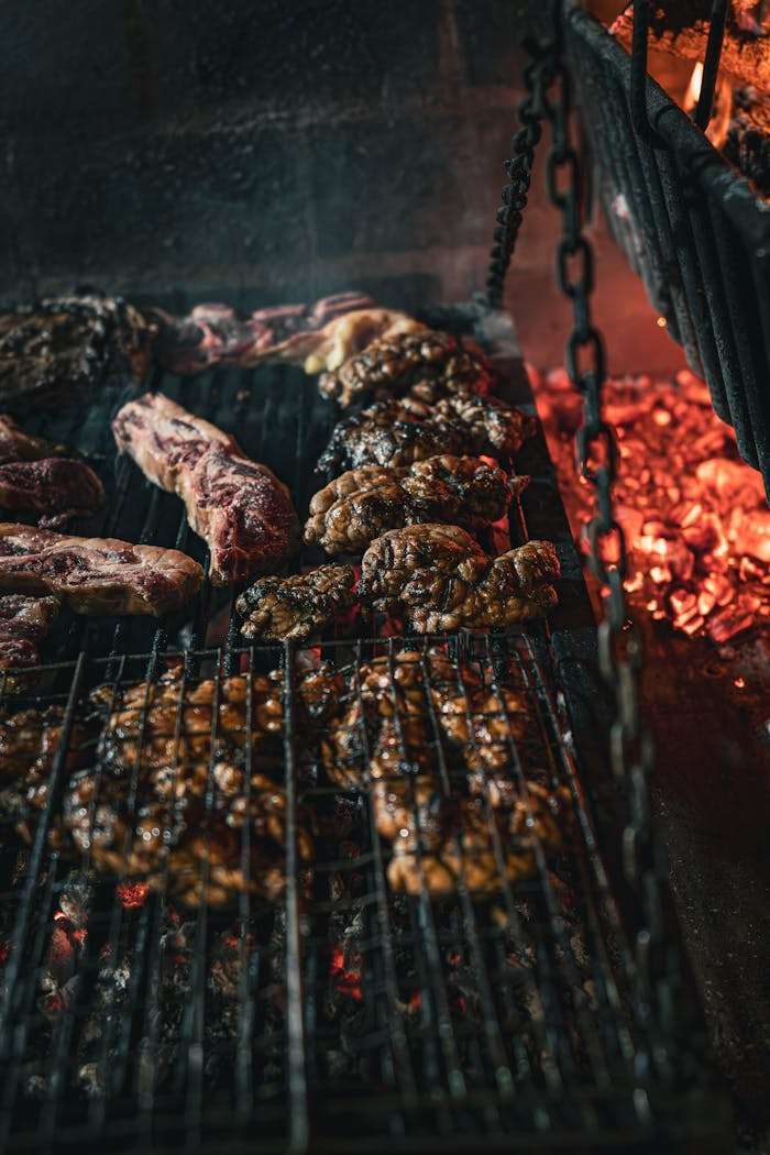 Close-up of a traditional Argentine barbecue with various meats grilling over hot coals.