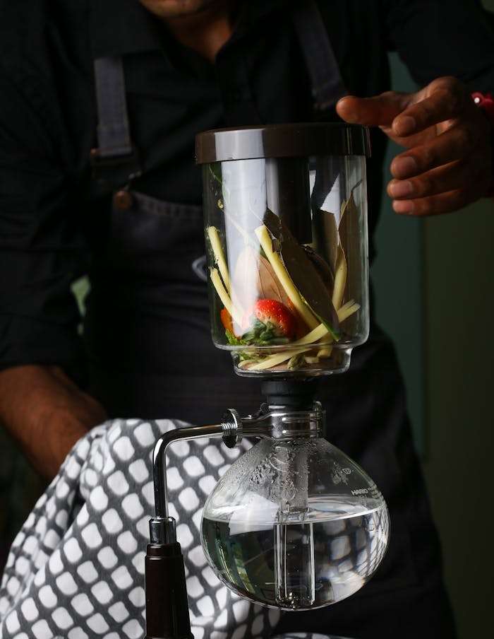 Bartender using a siphon for unique cocktail infusion with fresh ingredients indoors.